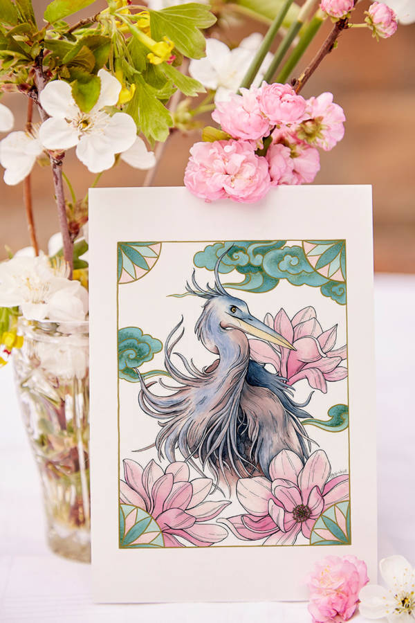 Carte illustrée Héron bleu et magnolias 3 Carte illustrée d'un héron aux plumes bleutées et grises entouré de magnolias roses et de motifs asiatiques, style aquarelle, fond blanc